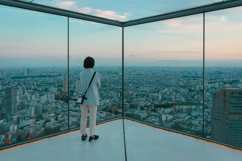 Посетитель на открытой смотровой площадке SHIBUYA SKY с панорамой Токио на закате